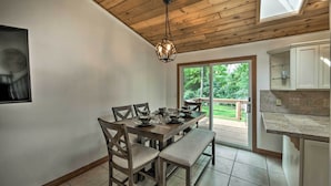 A dining area with a wooden table set for four, a bench, and a hanging light fixture. - Lake Nagawicka Home - 2 Blocks to Boat Launch (Delafield)
