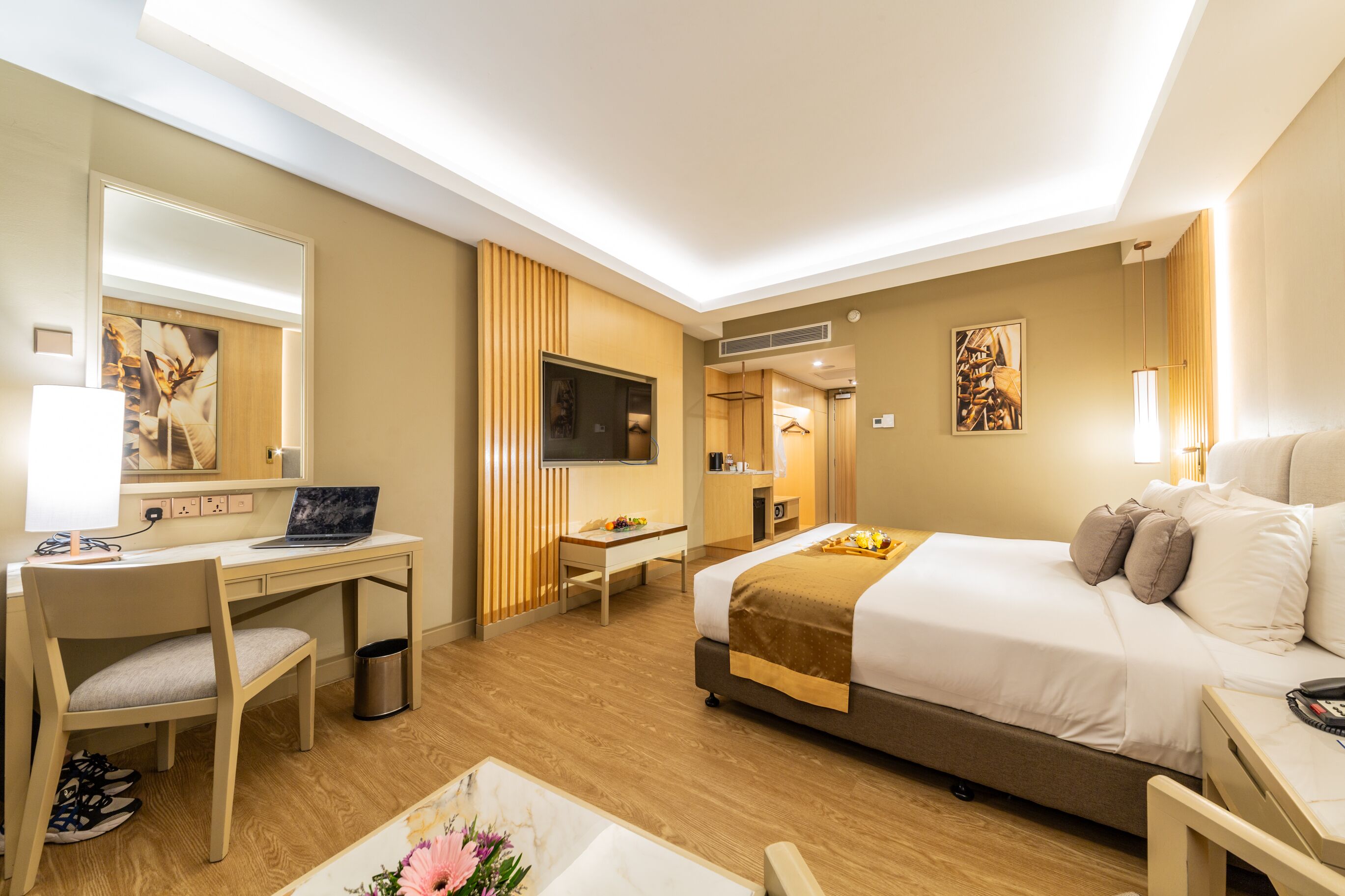 A hotel room with a bed, desk, chair, TV, and a small bathroom area.