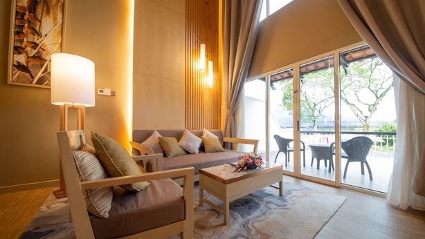 A modern living room with a sofa, two armchairs, a coffee table, and a large window with curtains. - Glenmarie Hotel & Golf Resort (Shah Alam)