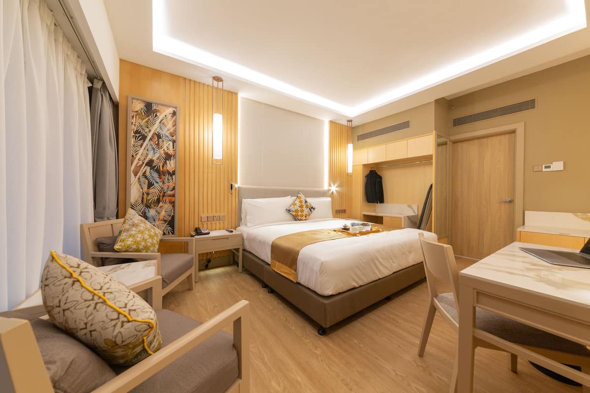 Una habitación de hotel con cama, escritorio, silla, mesita de noche y un amplio ventanal.