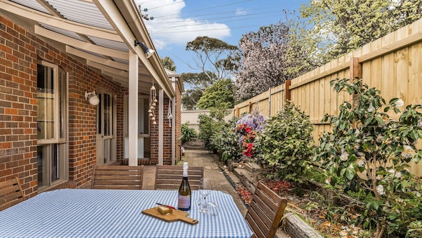 A patio with a table set for dining, a bottle of wine, and a glass. - Bayside walks and local beach access, in the heart of the Bellarine and wineries (Clifton Springs)