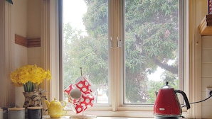 A kitchen counter with a red kettle, a yellow teapot, a polka-dotted cloth, and a vase of yellow flowers. - Bayside walks and local beach access, in the heart of the Bellarine and wineries (Clifton Springs)