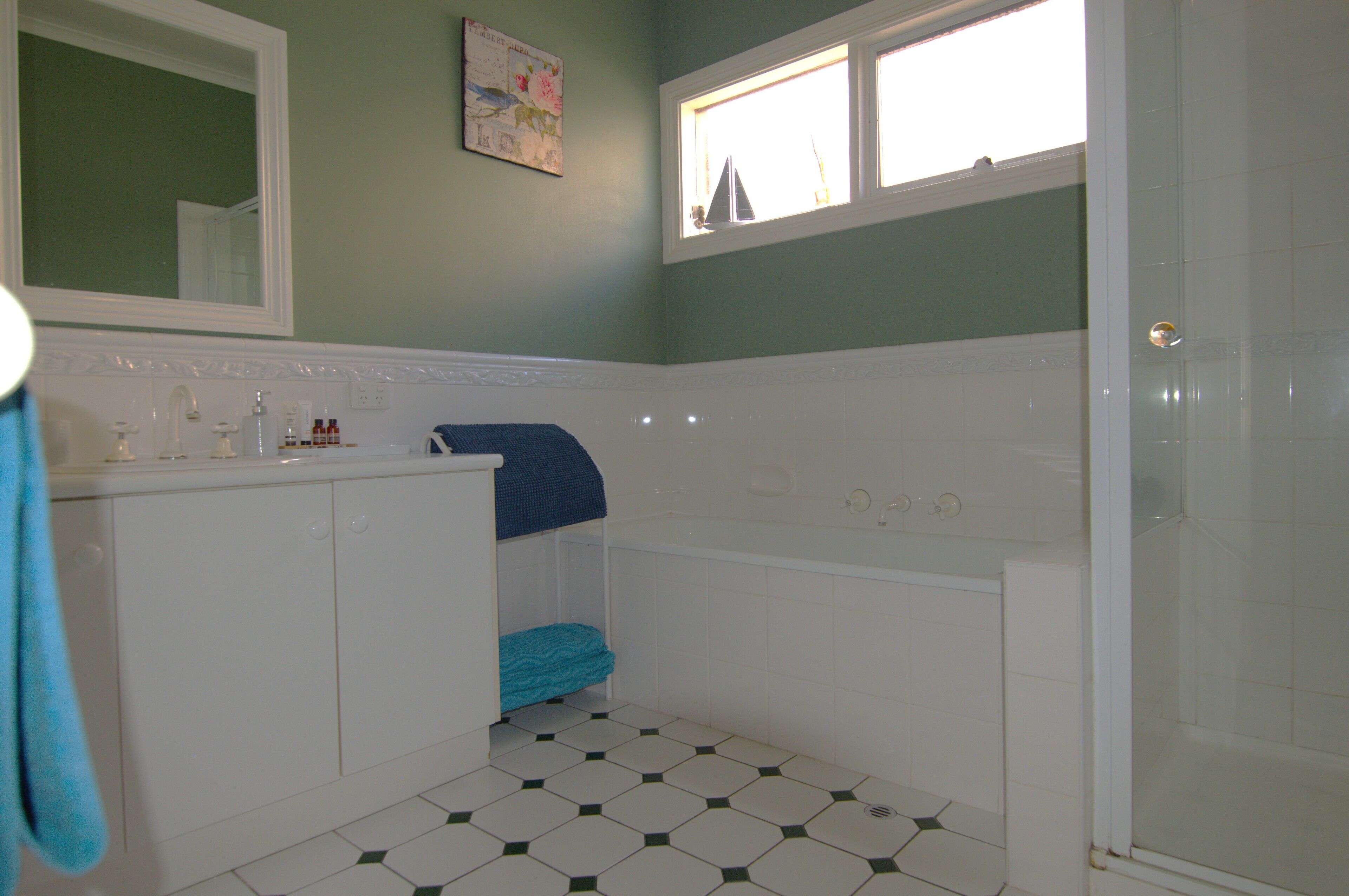 Een badkamer met een witte wastafel, een badkuip, een douche en een raam met uitzicht.