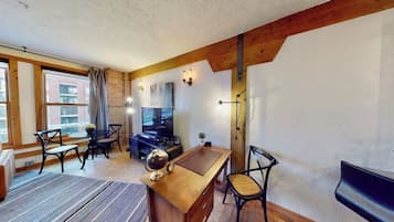 A room with a wooden desk, a globe, a piano, and a dining area with chairs and a table.