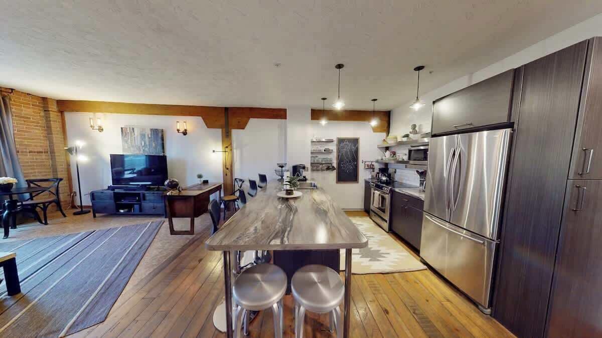 A modern kitchen with a central island, stainless steel appliances, and a dining area with a TV.