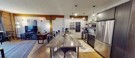 Uma cozinha moderna com uma ilha central, eletrodomésticos de aço inoxidável e uma área de refeições com televisão.