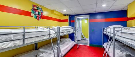 A dormitory room with bunk beds, a red carpet, and a colorful wall design.