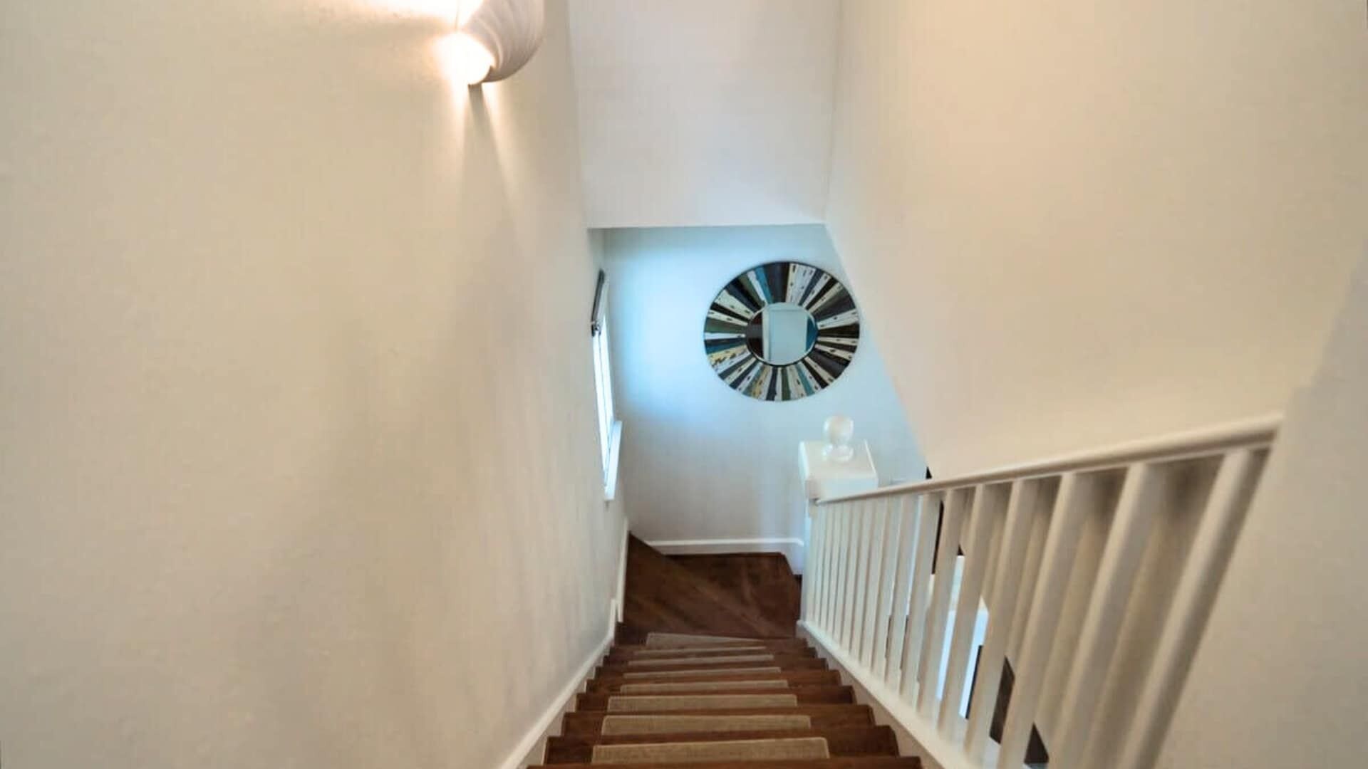 A staircase with a white railing and a wall-mounted clock.