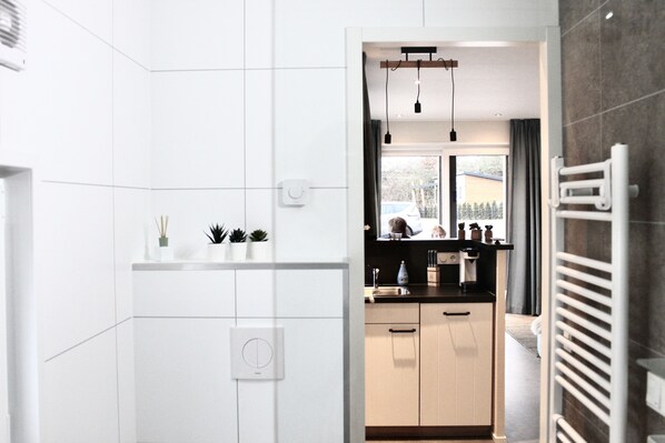 Eine moderne Küche mit weißen Schränken, einem eingebauten Backofen und einem Fenster mit Blick auf eine Wohngegend.