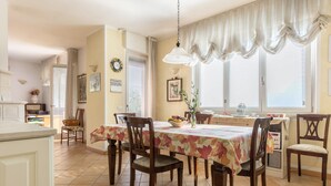 A dining area with a table set for six, surrounded by wooden chairs. - Holiday Apartment 'Casa Zanoni' with Lake View, Shared Garden, Balcony & Wi-Fi (Arco)