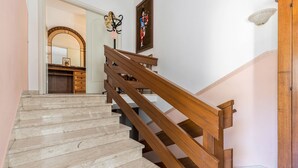 A staircase with wooden handrails and marble steps leading to a room with a wooden cabinet and a wall-mounted light fixture. - Holiday Apartment 'Casa Zanoni' with Lake View, Shared Garden, Balcony & Wi-Fi (Arco)