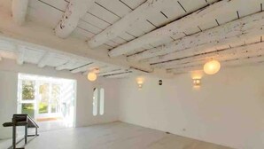 Une pièce spacieuse avec un plafond haut, des poutres apparentes et une grande fenêtre.