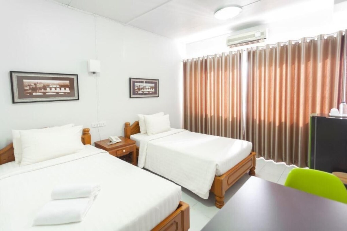 A hotel room with two beds, a desk, a chair, and curtains.