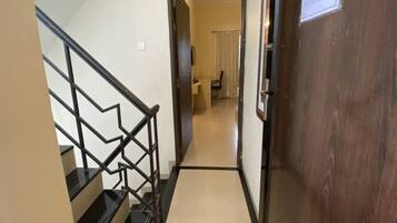 A staircase with black railings leading to a room with a wooden door and a visible light switch.