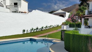 Ein Pool mit weißer Wand und einem Weg zu einem Gebäude.