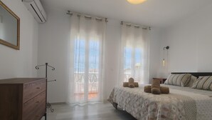 Ein Schlafzimmer mit einem Bett, einer Holzkommode, einem Spiegel und einer Klimaanlage.