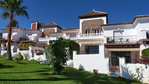 Ein mehrstöckiges Gebäude mit weißer Fassade, roten Ziegeldächern und Balkonen mit Geländern.
