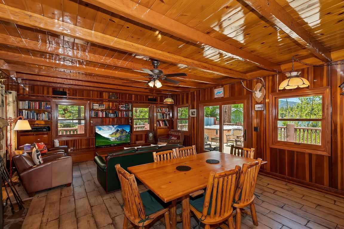 Un interior de madera con un comedor, estanterías y un televisor.
