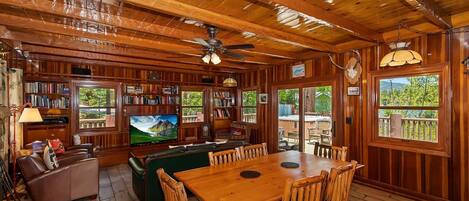 Un interior de madera con un comedor, estanterías y un televisor.