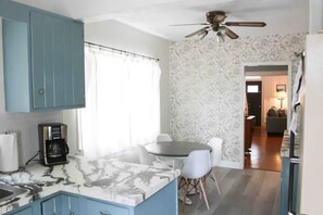 A kitchen with a marble countertop, a coffee maker, and a ceiling fan.