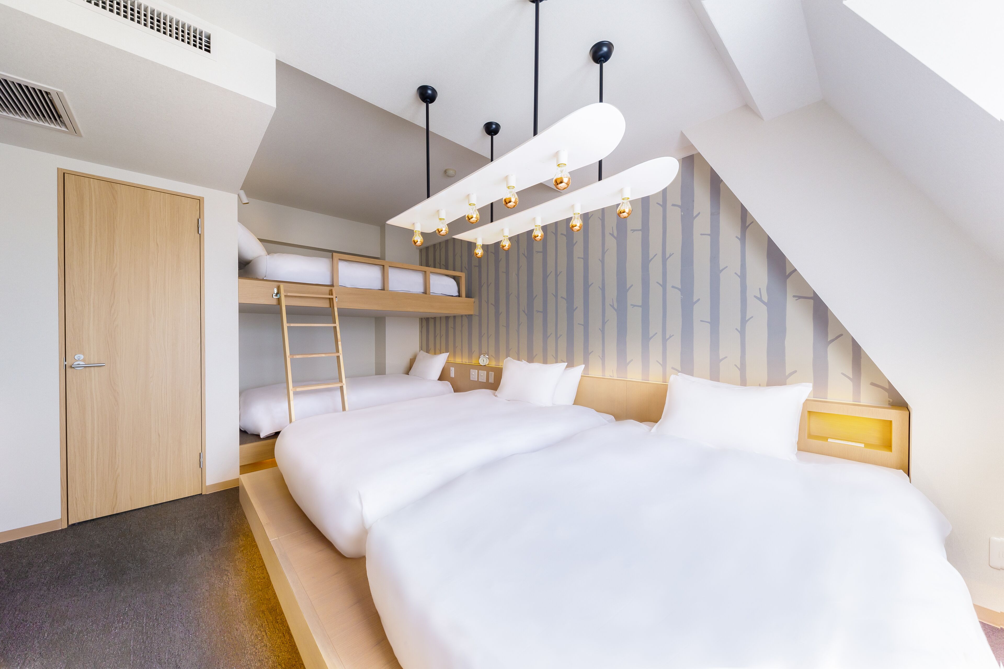 A modern bedroom with bunk beds, a wooden wardrobe, and a sloped ceiling with pendant lights.