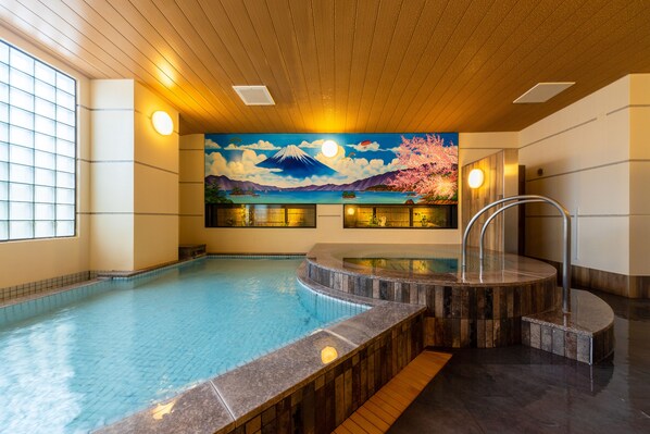 An indoor swimming pool with a hot tub, wooden ceiling, and a mural of Mount Fuji. - The Happo (Hakuba)