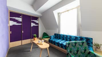 Ein Zimmer mit einer eingebauten Couch, einem kleinen Tisch mit einer Pflanze und einem Fenster mit Vorhängen.