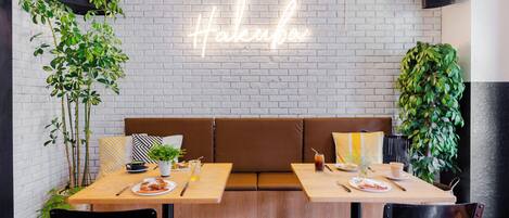A modern cafe with a neon sign, wooden tables, and cushioned seating.