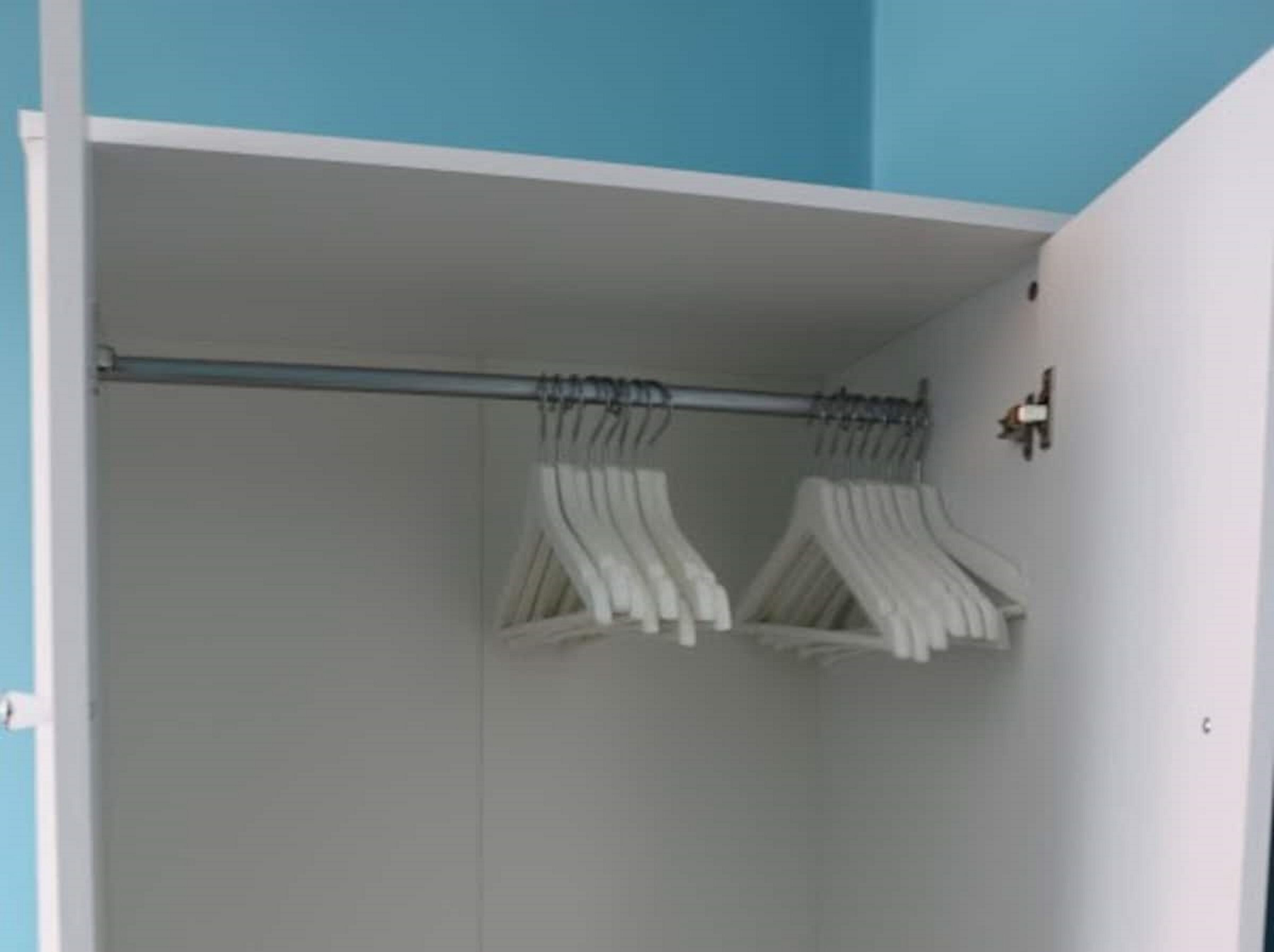 A walk-in closet with a metal rod for hanging clothes.
