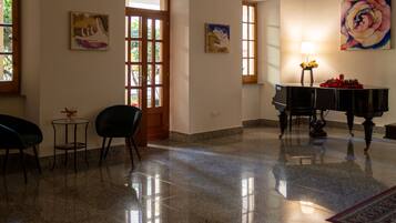 A spacious room with a polished floor, a piano, and two chairs.