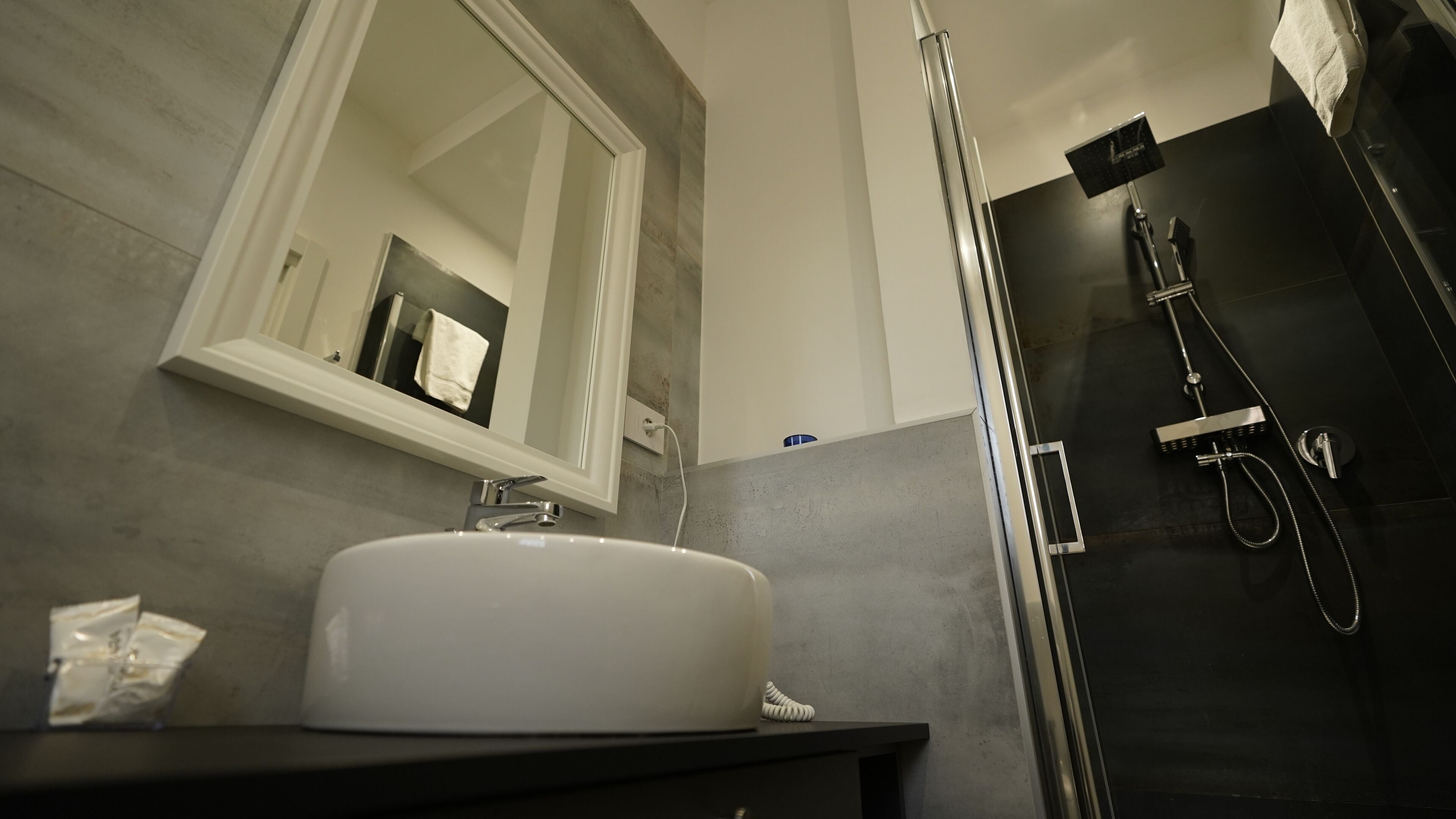 A bathroom with a white sink, a mirror, and a shower area.