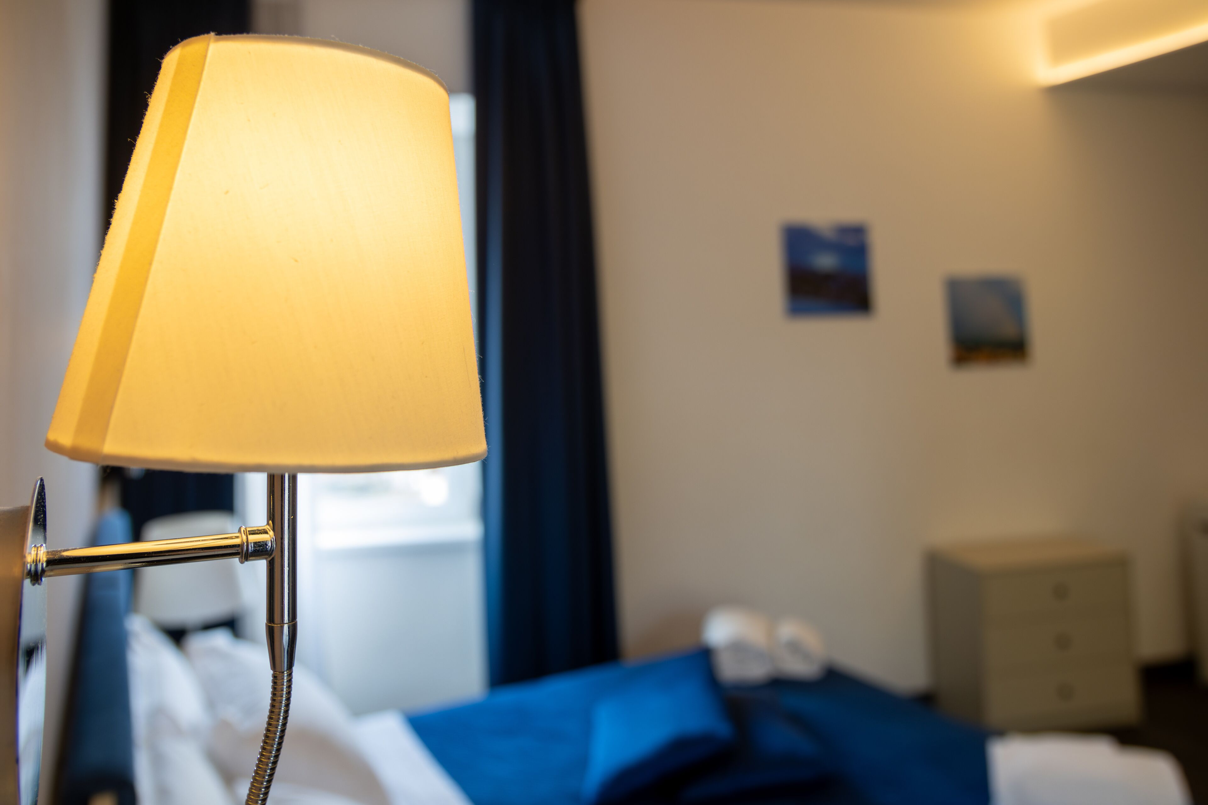 Et hotelværelse med en seng, et natbord og en lampe.