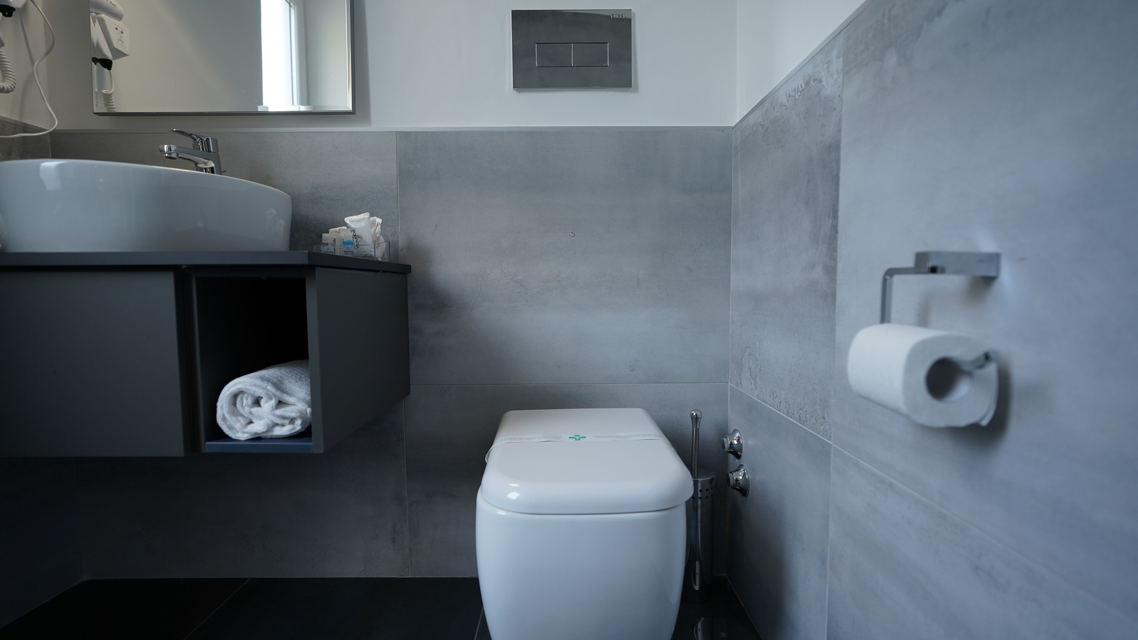 A modern bathroom with a white sink, a toilet, and a towel rack.