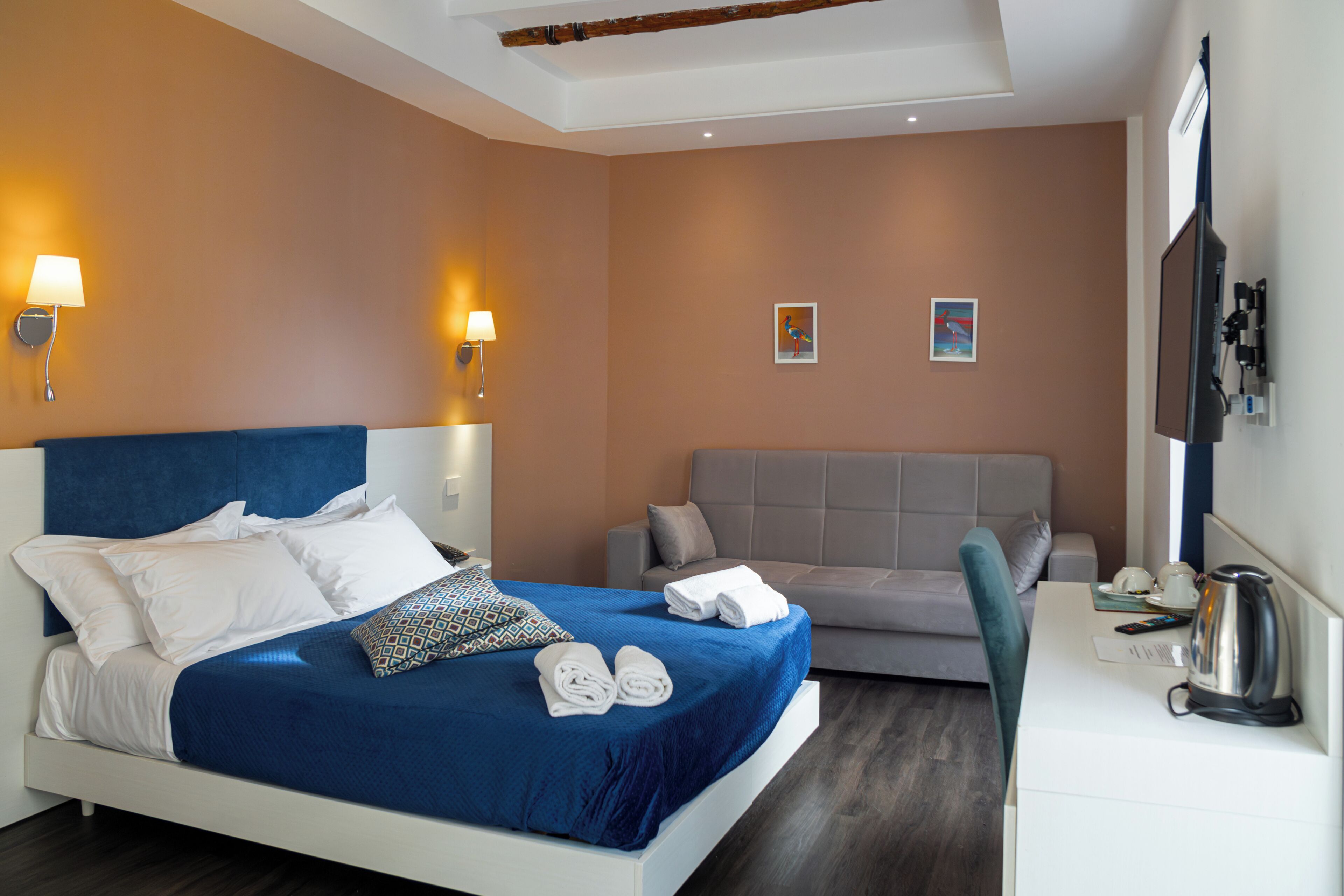 A hotel room with a bed, a sofa, a desk, and a TV.