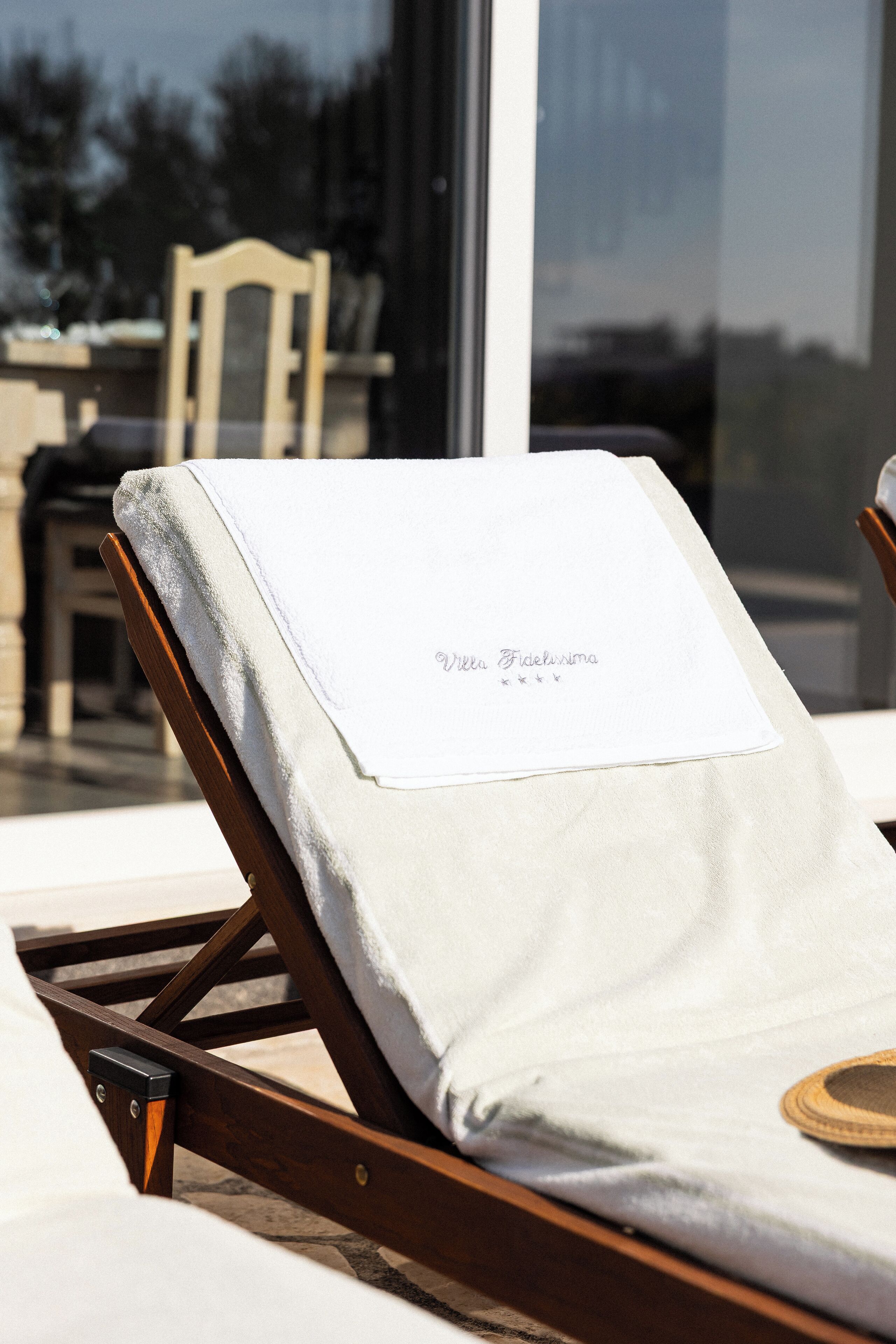 A wooden lounge chair with a white towel and a name tag.