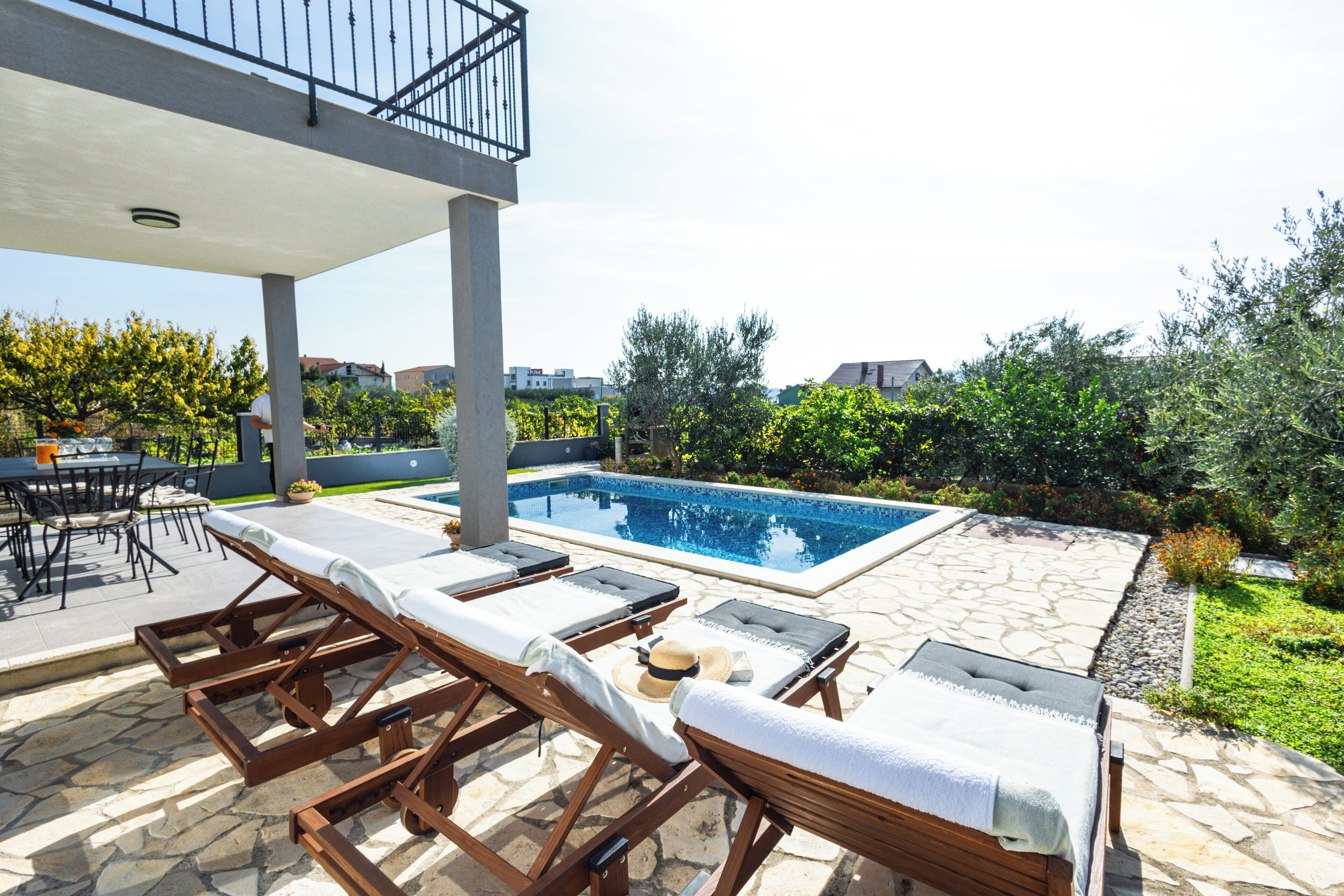 A pool area with lounge chairs, a table, and a covered seating area.