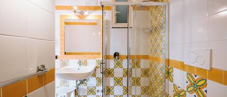 A bathroom with a glass shower enclosure, a sink, and a toilet.