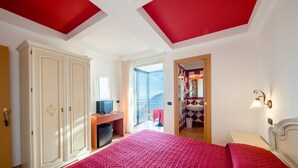 Un dormitorio con una cama grande, un armario, un escritorio y un baño visible a través de una puerta abierta.