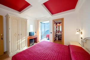 Un dormitorio con una cama grande, un armario, un escritorio y un baño visible a través de una puerta abierta.