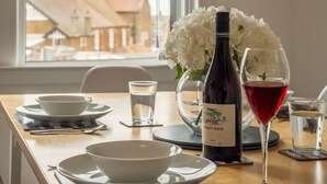 Una mesa para comer dispuesta con cuencos blancos, una botella de vino y una copa de vino tinto.