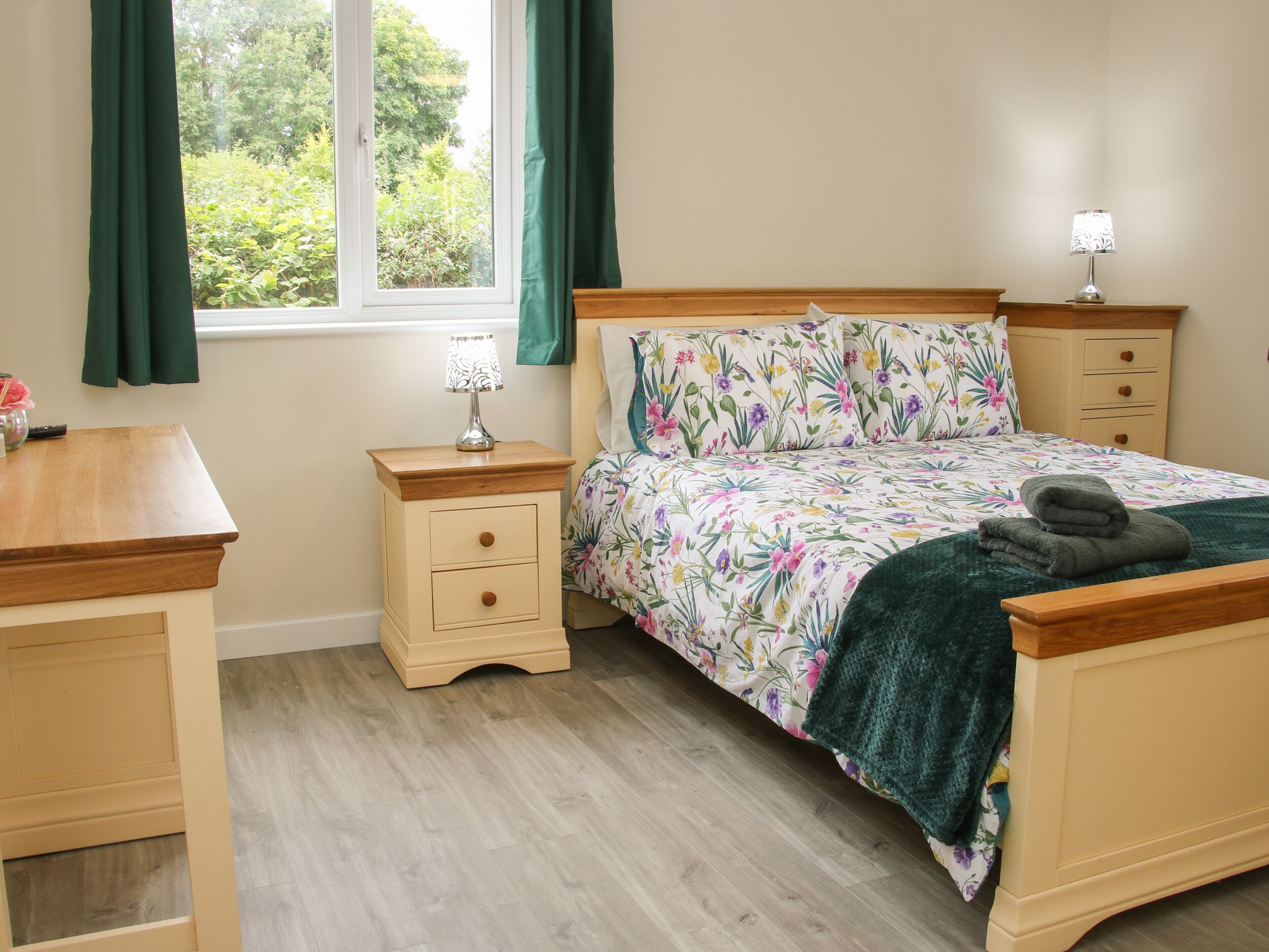 A bedroom with a bed, a bedside table, a lamp, and a window with curtains.