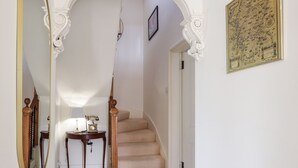 A hallway with a mirror, a small table with a telephone, and a staircase. - Mary Ann Villa (Inverness)