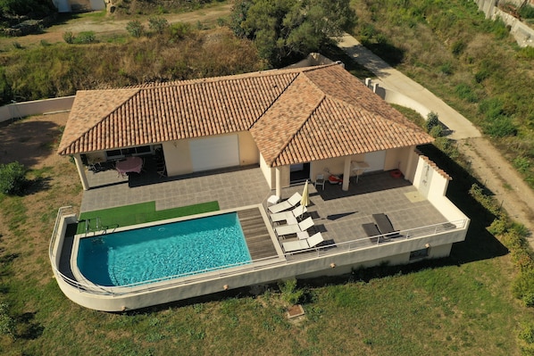 Uma casa de dois andares com piscina, área de estar externa e jardim.
