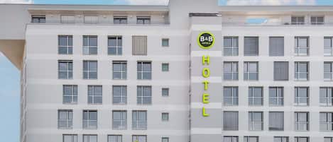 Un moderno edificio hotelero con varios pisos, amplias ventanas y un llamativo letrero de B&B Hotels.