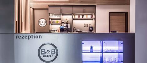 A reception area with a modern design, featuring a reception desk, a bar area, and a display of glassware.