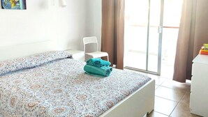 Une chambre à coucher avec un lit, une chaise, un tableau et une porte-fenêtre coulissante.