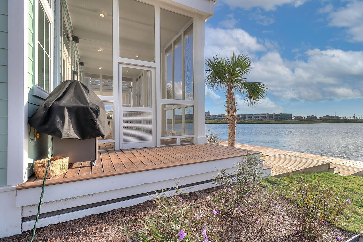 A waterfront property with a covered porch, a palm tree, and a view of the water.