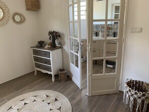 Una habitación con un aparador blanco, un tapete redondo tejido y un mueble con puertas de cristal y cajones.