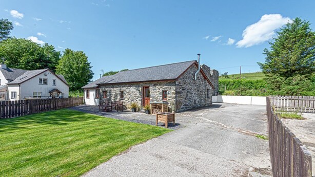 A stone house with a gravel driveway and a wooden fence.