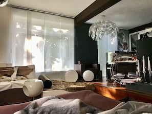 Ein modernes Wohnzimmer mit großem Fenster, einer Kronleuchter und einem Fernseher.